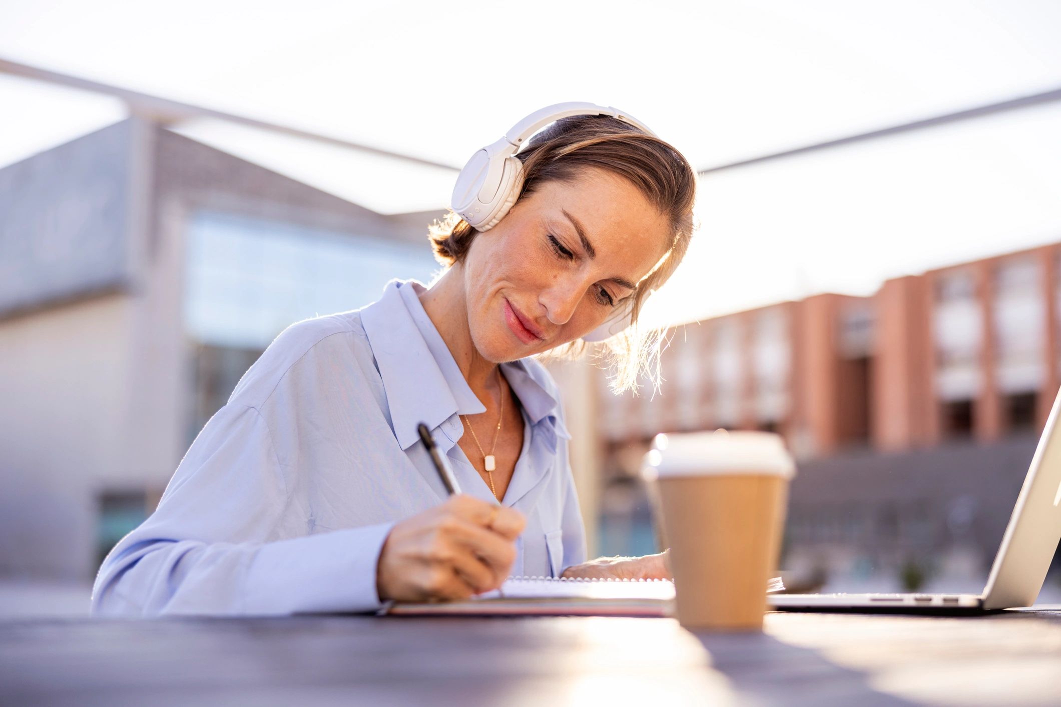 Professional woman taking notes while working on a computer