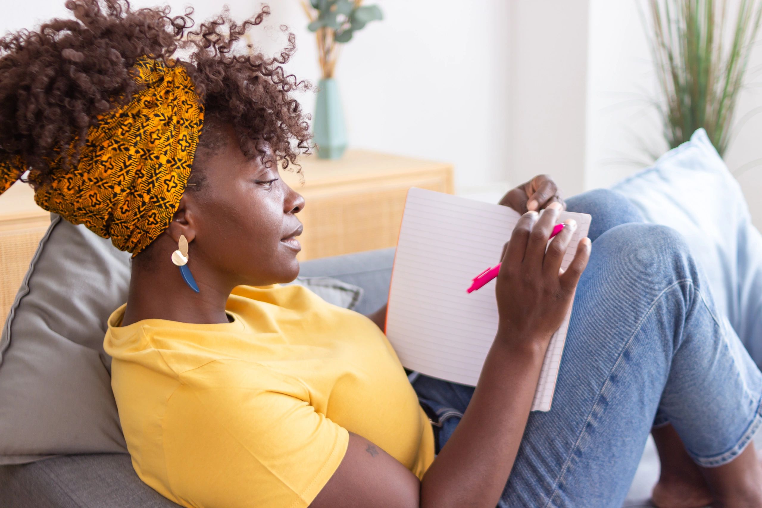 Woman writing in notebook on couch