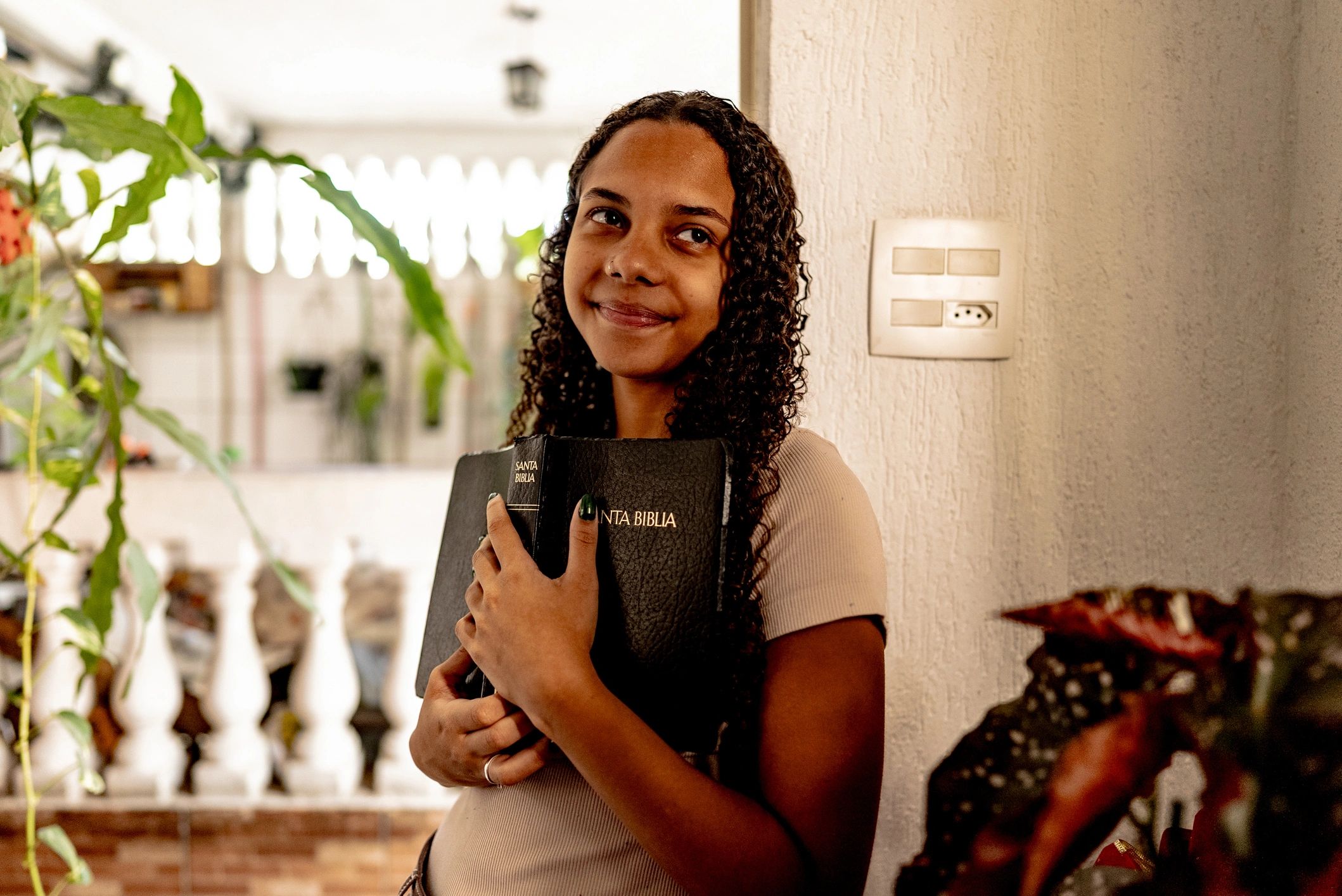 Young woman looking away holding bible at home