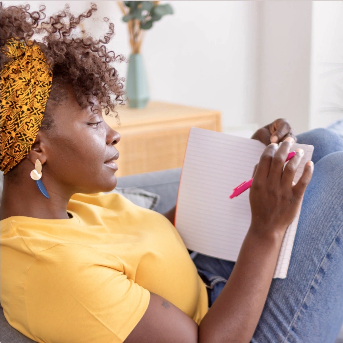 Woman writing in a notebook on a couch